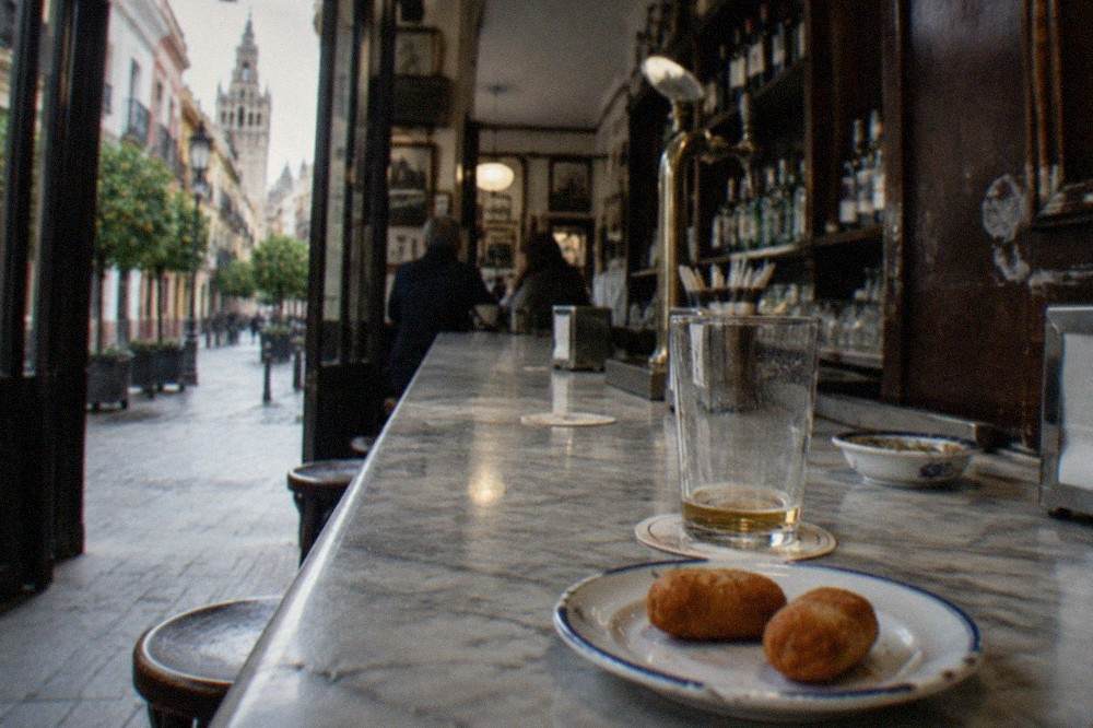 Small tapas dishes and glasses on a marble bar counter in Seville