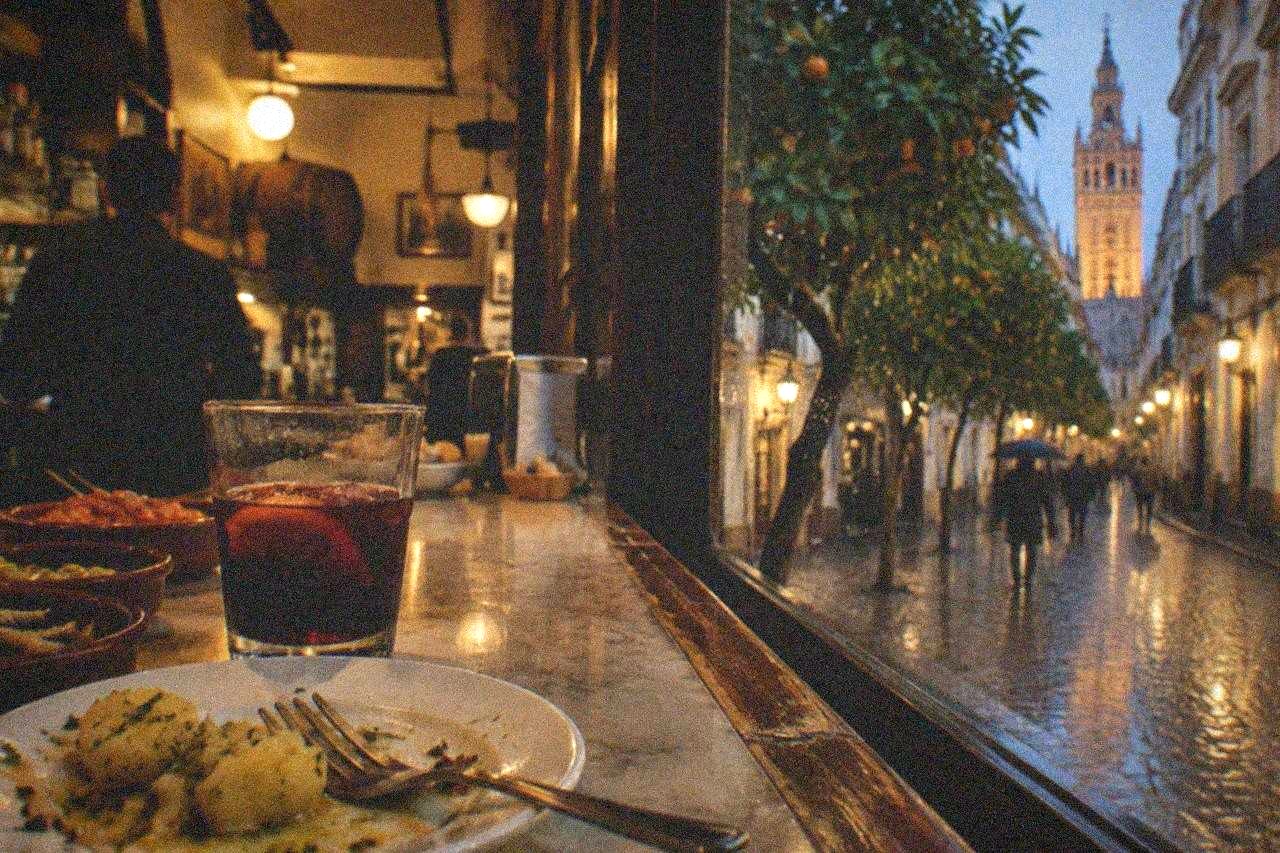 Small tapas dishes arranged on a wooden bar counter in Seville