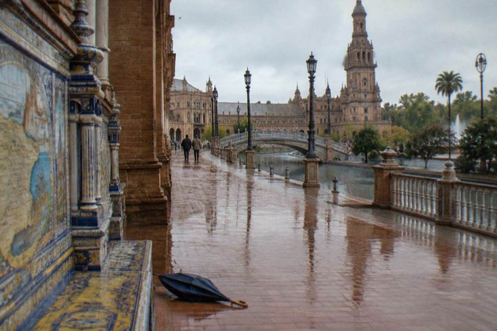 An open plaza in Seville with tiled alcoves and a long reflecting pool