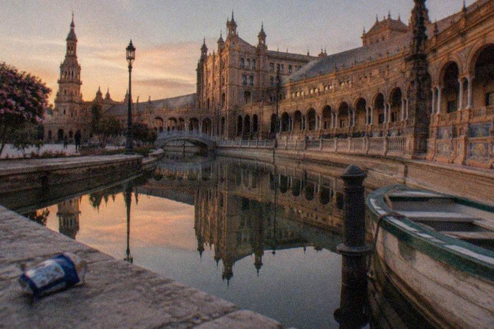 The curved brick facade of Plaza de España reflected in its canal