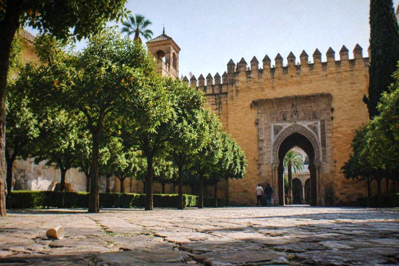 Tiled arches and manicured hedges in a courtyard of the Real Alcázar of Seville