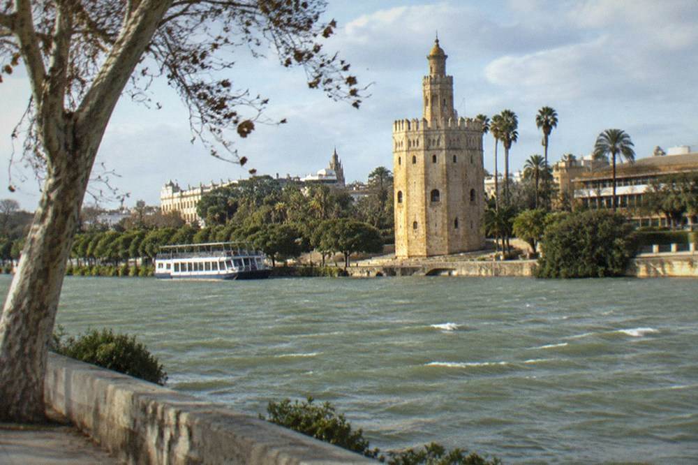 Riverside promenade beside the Guadalquivir with the Torre del Oro across the water