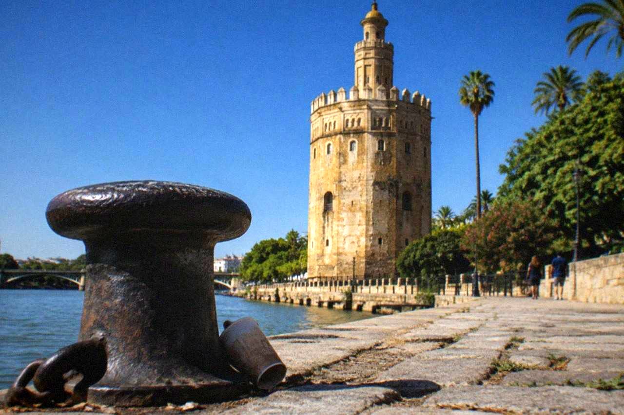 The golden stone Torre del Oro tower standing beside the Guadalquivir river