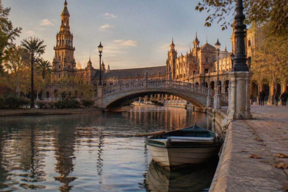 Plaza semicircular con azulejos, un canal, puentes y torres con pináculos en Sevilla