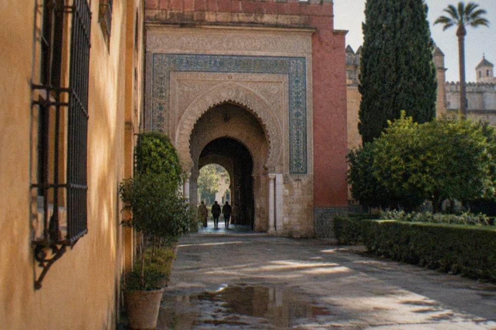 Ornate carved archways and tiled walls inside a Moorish palace courtyard in Seville