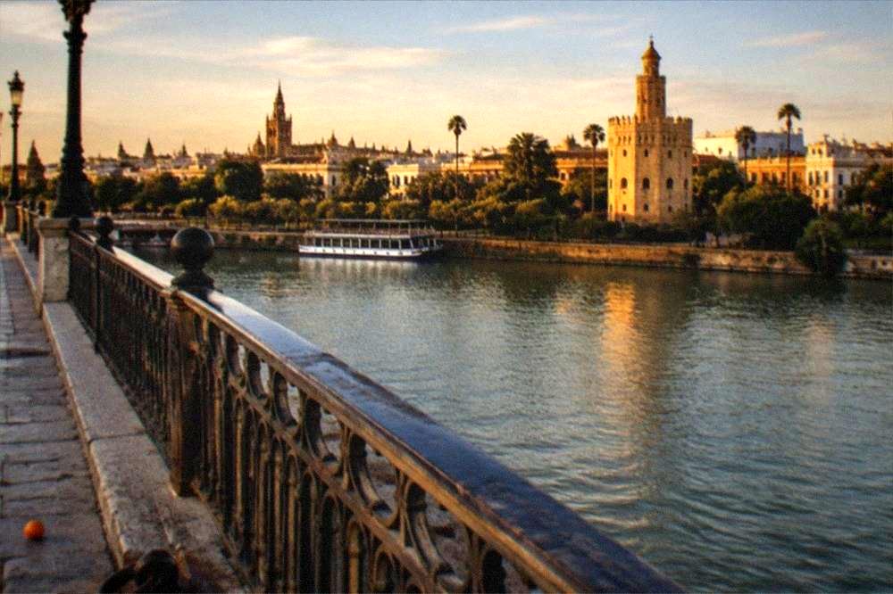 Triana bridge crossing the Guadalquivir River with facades behind it in late afternoon light