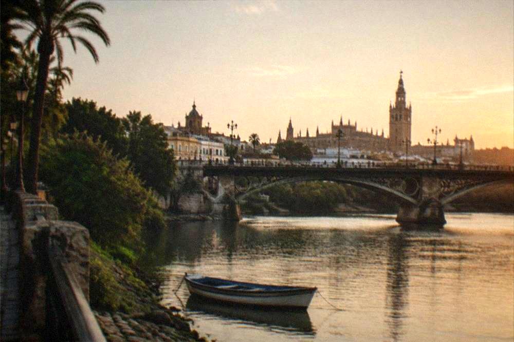 A riverside Seville bridge and old district buildings in late afternoon light