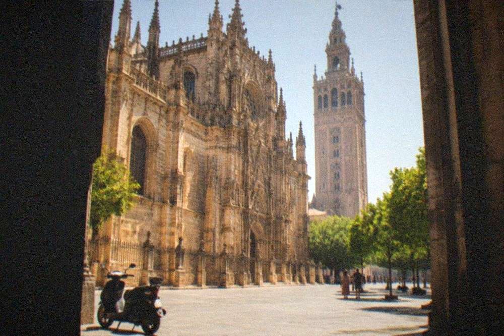 Gothic cathedral facade and bell tower seen from an open square