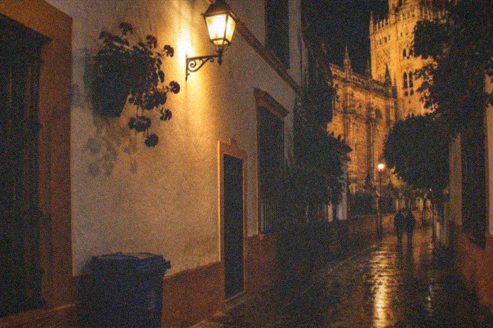 Seville street at night with lit historic facades