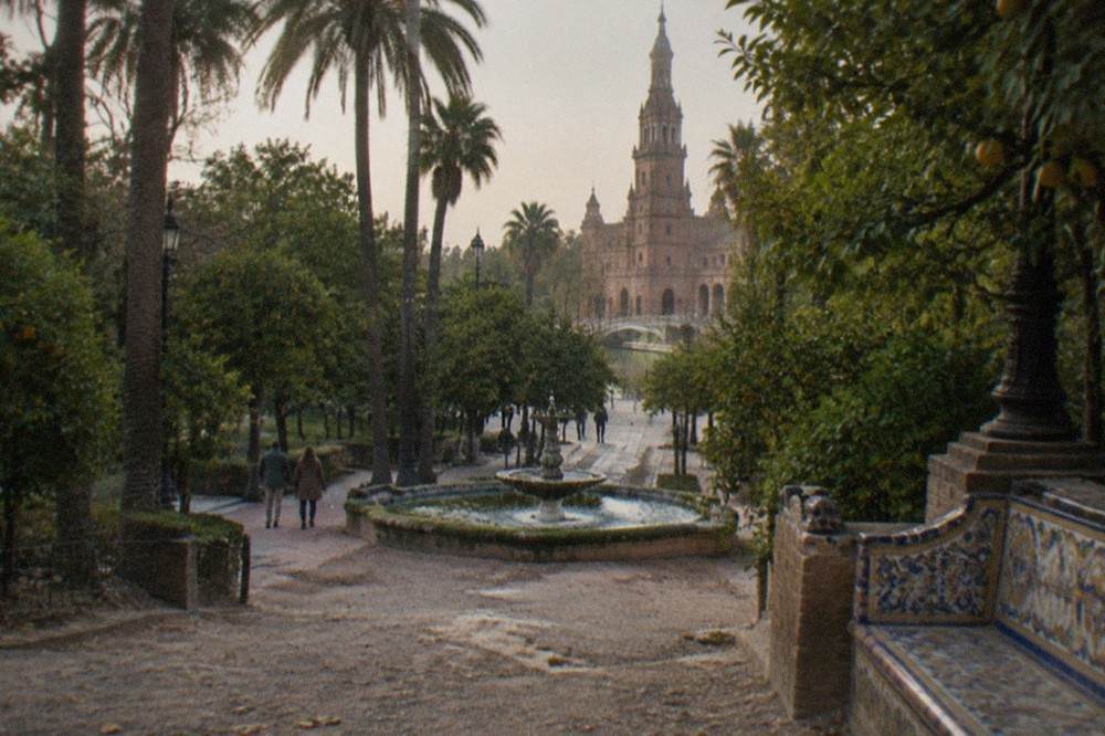 Palm-lined park avenue with tiled benches, stone fountains and shaded walkways in daylight