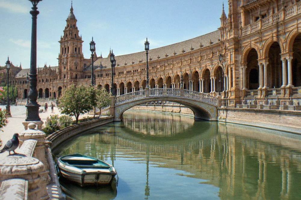 Semicircular plaza with a canal, arched footbridges and tiled alcove benches in daylight