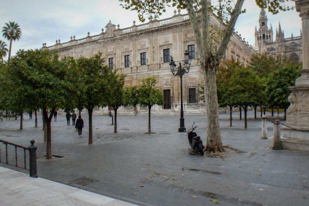 Open plaza with orange trees and ornate historic facades in Seville
