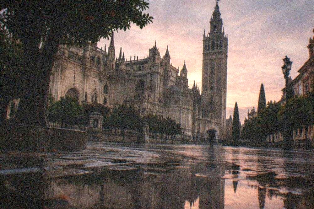 Gothic cathedral facade and bell tower rising above a Seville square