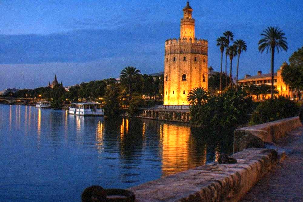The Torre del Oro tower seen from across the Guadalquivir river at dusk.