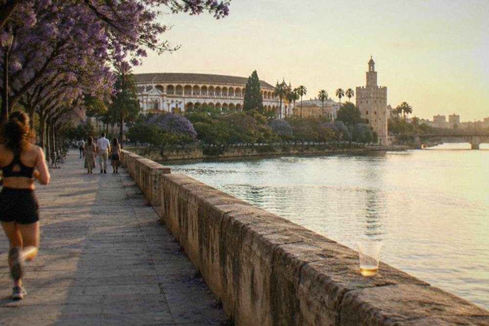 The riverside promenade beside the Guadalquivir River with the stone wall of the bullring district