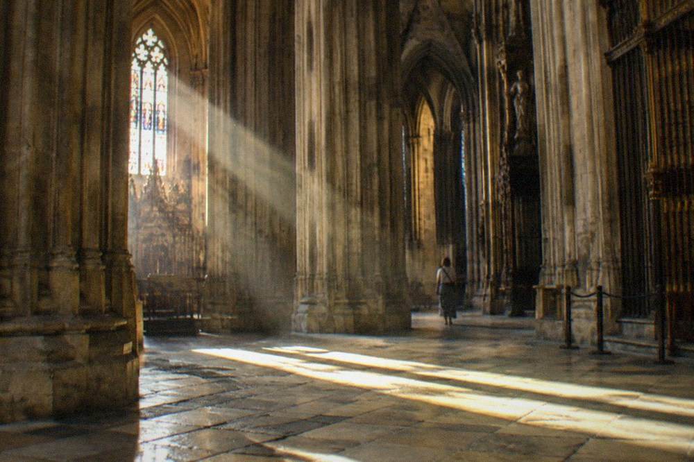 Sunlight falling across the stone floor inside Seville Cathedral, columns rising to a vaulted ceiling