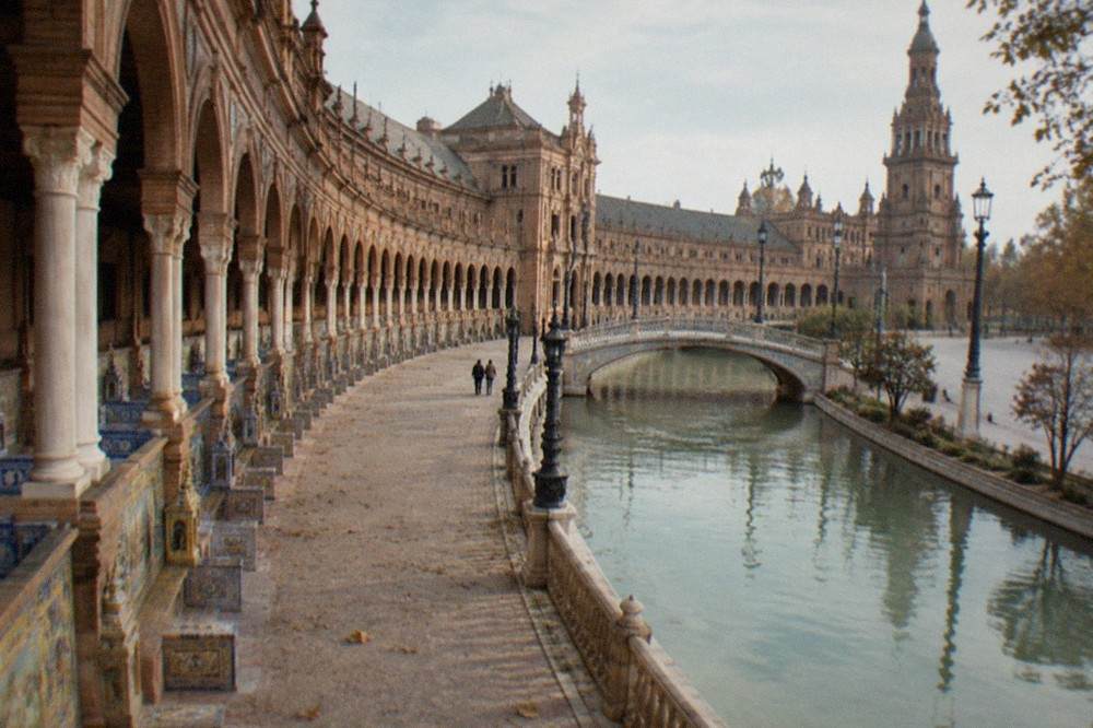 Wide view of a semicircular plaza with tiled benches and a canal