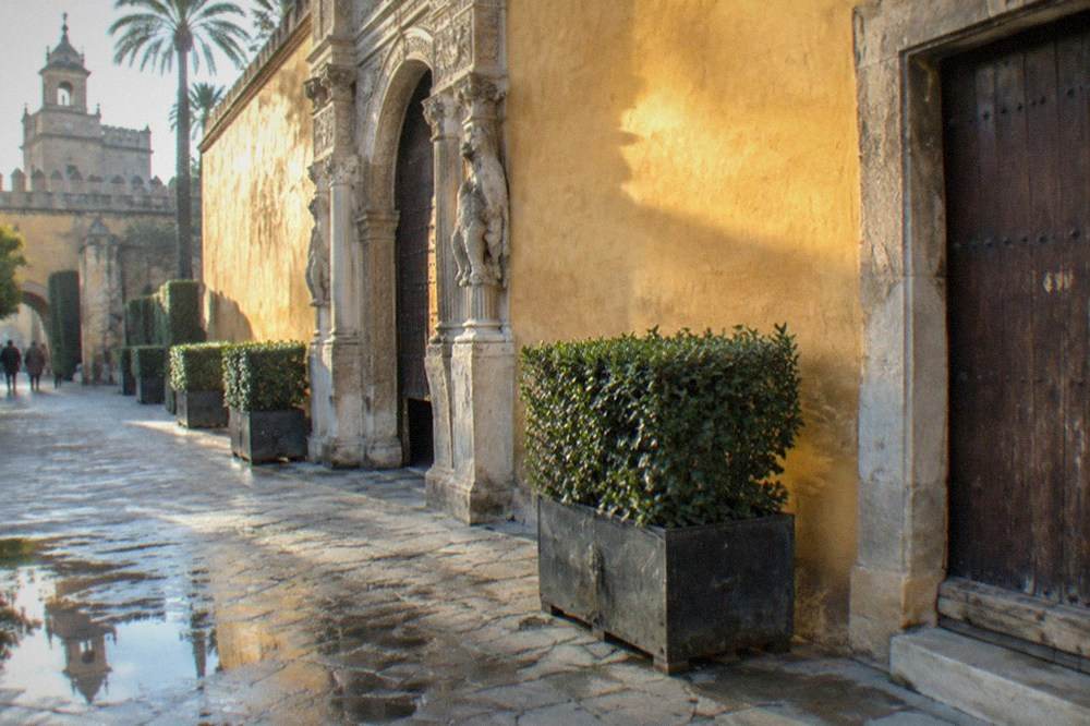 Ornate walled palace courtyard with arches and green gardens