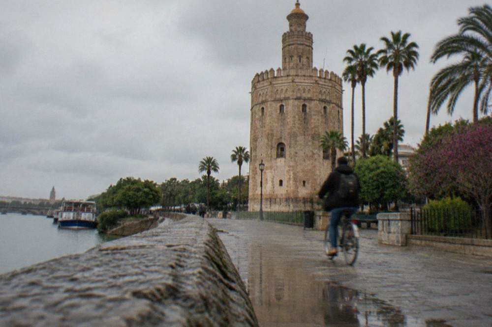 The golden stone tower of the Torre del Oro seen from the Guadalquivir riverbank